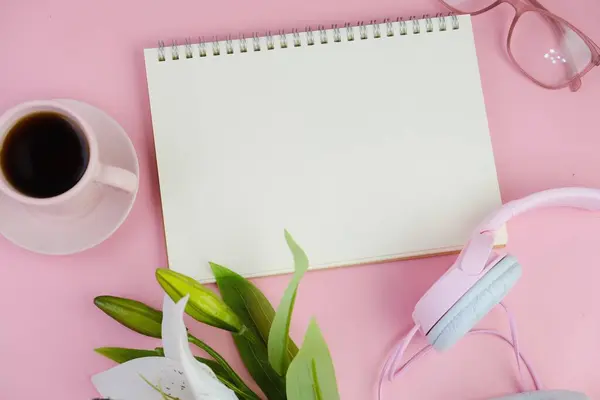 Pembe ofis aletleri, pembe kulaklık, not defteri, kalem ve pembe arka planda bir buket pembe lale fotokopi alanı konsepti.