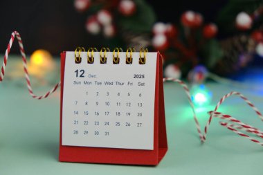 Aralık 2024 tarihli aylık masa takvimi siyah alarmlı ahşap masada. Noel teması