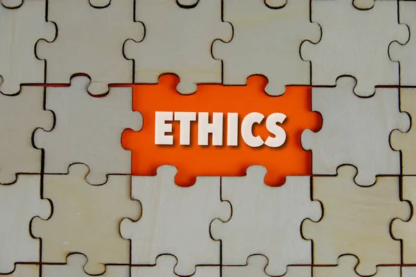 Ahşap yapbozun kayıp parçası ile ilgili etik kelimeler harfler, etik ahlak felsefesi kavramı, iş ve yönetim kavramı. Turuncu arkaplan. 