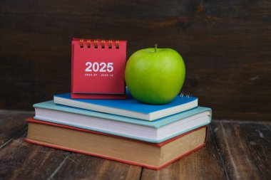 Takvim ve yeni yıl konsepti. Renkli kalemler, lacivert arka planda 2025 yılının kırmızı mini takvimi. renkli ışıklar. 