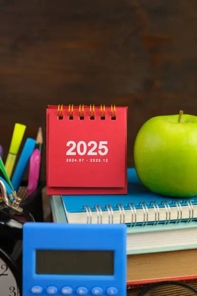 Takvim ve yeni yıl konsepti. Renkli kalemler, lacivert arka planda 2025 yılının kırmızı mini takvimi. renkli ışıklar. 