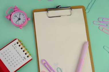 Metin alanı için boş bir not defterinin düz uzantısı. Pembe arka planda metin alanı olan eğitici bir kavram. kalem, alarm saati ve hesap makinesi gibi sarı araçlarla çevrelenmiş