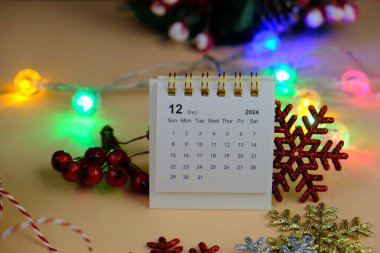 Aralık 2024 tarihli aylık masa takvimi siyah alarmlı ahşap masada..