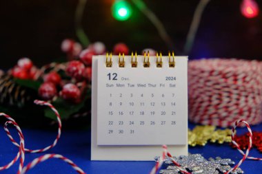 Aralık 2024 tarihli aylık masa takvimi siyah alarmlı ahşap masada..