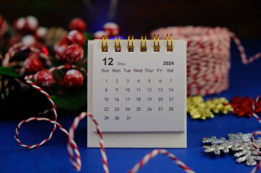 Aralık 2024 tarihli aylık masa takvimi siyah alarmlı ahşap masada..