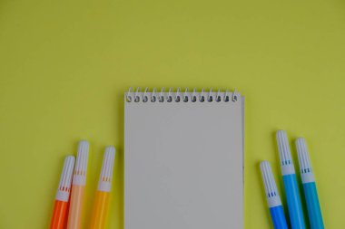 flat lay of a blank note book for text space. Educational concept with text space on yellow background. surrounded by yellow tools such as pen, alarm clock and calculator clipart