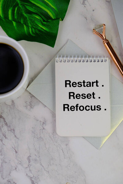 Morning inspirational motivational words - Restart. Reset. Refocus. Text on book page with pen, cup of coffee on white background. Restart. Positive motivational words on book page