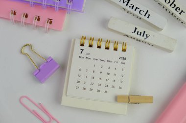 Bir ofis arka planında Temmuz 2025 için aylık masa takvimi. 