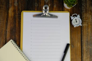 Günlük, kalem, dizüstü bilgisayar, kahve fincanı ve gri arka planda dekor bitkisi olan boş bir çalışma alanı. Üst manzara, düz yatış. kontrol listesi konsepti