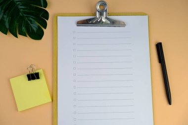 Günlük, kalem, dizüstü bilgisayar, kahve fincanı ve gri arka planda dekor bitkisi olan boş bir çalışma alanı. Üst manzara, düz yatış. kontrol listesi konsepti