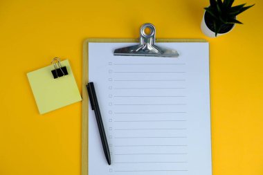 Günlük, kalem, dizüstü bilgisayar, kahve fincanı ve gri arka planda dekor bitkisi olan boş bir çalışma alanı. Üst manzara, düz yatış. kontrol listesi konsepti