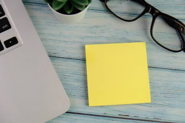 Günlük, kalem, dizüstü bilgisayar, kahve fincanı ve gri arka planda dekor bitkisi olan boş bir çalışma alanı. Üst manzara, düz yatış. kontrol listesi konsepti