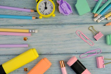 Canlı sarı bir arka planda okul malzemeleri çeşitliliğinin üst görüntüsü. Bu resim renkli kalemler, defterler, makas, silgi ve ataçları içeriyor, hepsi de okula dönüş için düzgünce yerleştirilmiş.