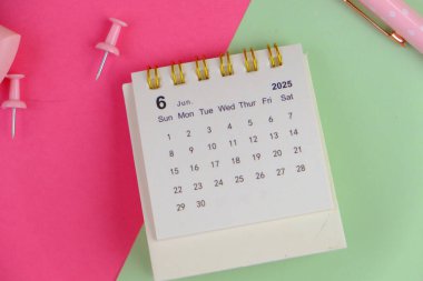 2025 yılı için ofis pembe arka planında aylık masa takvimi. 