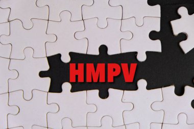 Üzerinde HMPV yazılı bir levha tutan eldiven giymiş bir sağlık görevlisinin resmi. Arka planda steteskop ve tıbbi maske var. İnsan metafnömotorirüsünün (HMPV) belirtileri ciddiyette değişebilir.