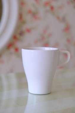 Pembe çiçek duvar kağıdıyla pembe ve yeşil bir temanın üst görüntüsü ve mesajınız için kısmen görünür beyaz bardak seti, aşk, yumuşak, kadınsı ve romantik konsept.