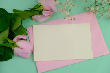 Sade bir arkaplana yerleştirilmiş şablon çiçekleri. Mesaj alanı ve sevgililer günü için bir model. Beyaz kağıt davetiye kartı. Zarf ve çiçeklerle maket. Kopya alanı ile maket.