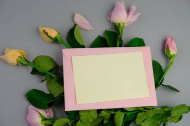 Sade bir arkaplana yerleştirilmiş şablon çiçekleri. Mesaj alanı ve sevgililer günü için bir model. Beyaz kağıt davetiye kartı. Zarf ve çiçeklerle maket. Kopya alanı ile maket.