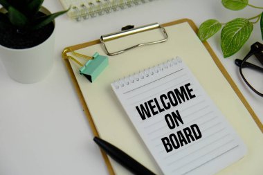 Not defterinin yanında kahve ve hesap makinesiyle birlikte duran bir kartvizitin üzerine 