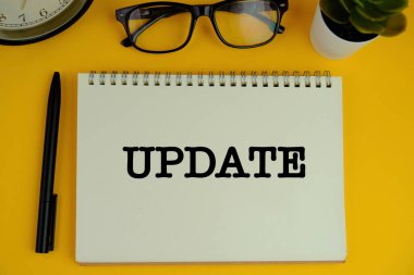 Not defteri, klavye, dekoratif vazo ve tahta zemin üzerinde dolmakalem olan UPDATE metni. İş ve kopyalama alanı kavramı