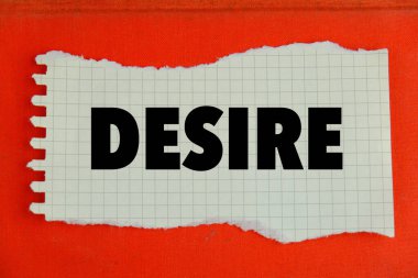 Arzu metni konsepti. DESIRE sözcüğü, turuncu arkaplandaki hesap makinesinde beyaz bir kartvizit üzerine yazılmış metin. 