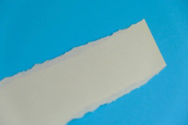 Beyaz kağıttaki yırtık mavi arkaplanı gösteriyor. Metin için boşluk.