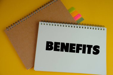 Laptopun yanındaki kahverengi zarfın içindeki düz kartta BENEFITS 'in metni. iş kavramı. 