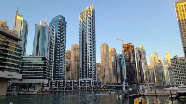 Bu fotoğraf Dubai 'de etkileyici gökdelenleri ve lüks liman manzaralarıyla bilinen modern bir bölge olan Dubai Marina' nın çarpıcı ufuk çizgisini yakalar. Uzun, parlak binalar batan güneşin altın rengini yansıtırken, tekneler ve yatlar...