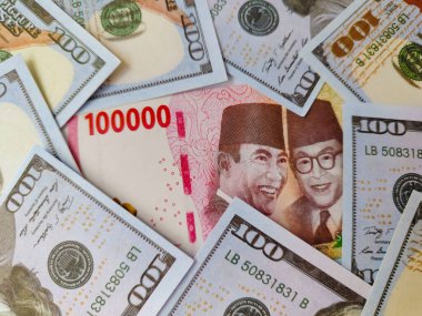 100 dolarlık banknotları ve Endonezya para birimlerini kapatın. Endonezya banknotu doların ortasında