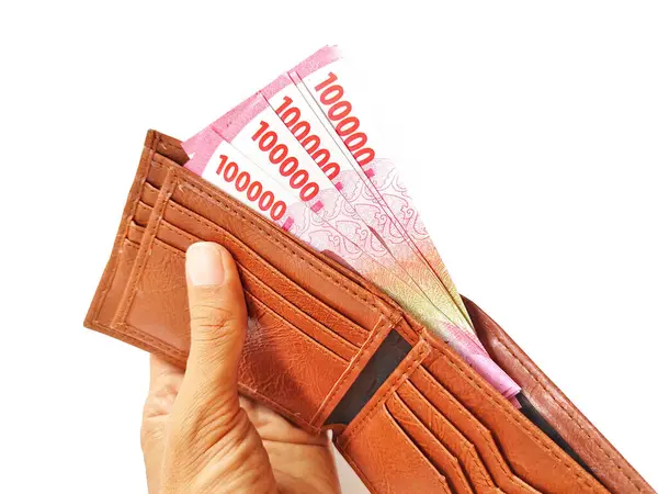 Rupiah notları olan bir cüzdan tutan kadın eli.