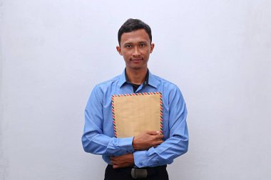 Genç Asyalı bir adam içinde CV olan kahverengi bir zarfı iş görüşmesine hazır tutuyor.