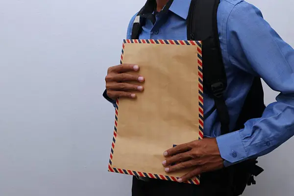 Bir çanta taşıyan ve içinde iş aramaya hazır özgeçmiş olan kahverengi bir zarf tutan Asyalı genç bir adamın yakın plan fotoğrafını çek.