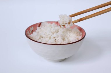 pirinç kasede, yemek çubukları da beyaz arka planda.