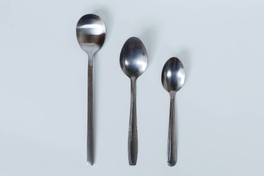 Beyaz arka planda üç çeşit kaşık. Çay kaşıkları, yemek kaşıkları ve Kore kaşıkları.