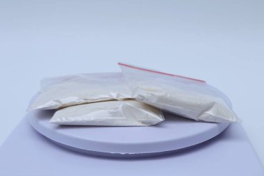 Beyaz çantalı beyaz bir tabak ve siyah arka planda beyaz bir poşet.