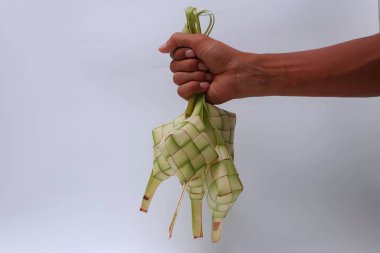 Beyaz arka planda ketupa dokunan eller. Kurban Bayramı 'nda geleneksel Endonezya yemekleri                        