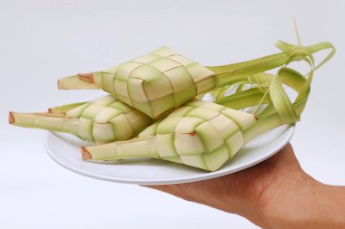 Beyaz arka planda ketupat dolu tabakları tutan eller. Kurban Bayramı 'nda geleneksel Endonezya yemekleri