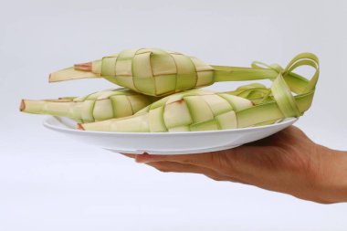 Beyaz tabakta ketupayı tutan el.