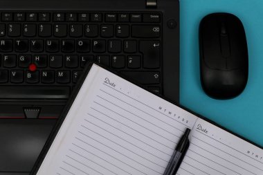 Bir dizüstü bilgisayara bir kalem konur ve mavi masadaki bir farenin yanına..                    