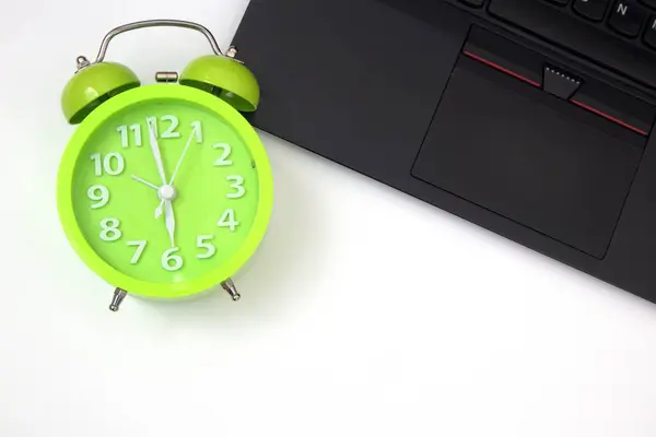 Beyaz arkaplanda dizüstü bilgisayar ve alarm saati