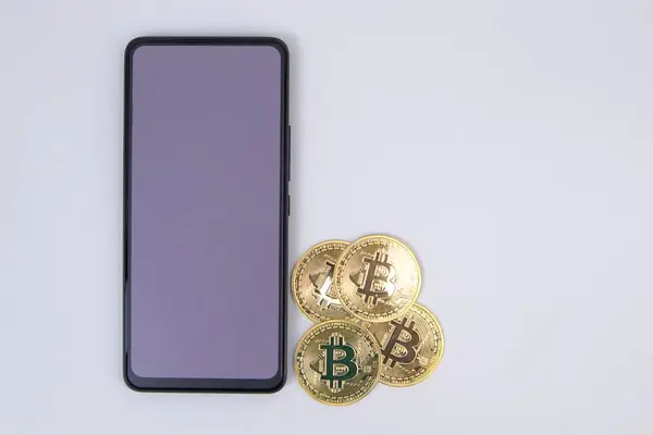 Beyaz arkaplanda bitcoin ve akıllı telefon