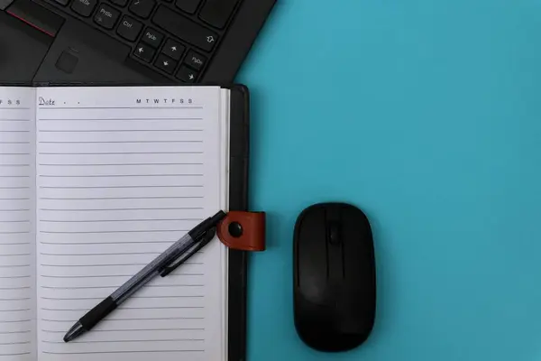 Bir dizüstü bilgisayara bir kalem konur ve mavi masadaki bir farenin yanına..                    