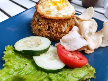 Kızarmış pirinç, yumurta soslu ve domates, salatalık ve marullu garnitür.