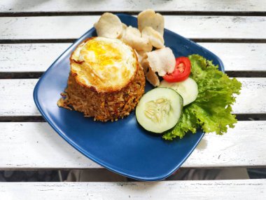 Kızarmış pirinç, yumurta soslu ve domates, salatalık ve marullu garnitür.