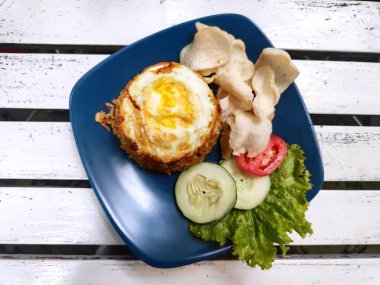 Kızarmış pirinç, yumurta soslu ve domates, salatalık ve marullu garnitür.