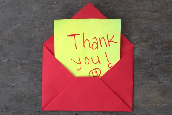 Kırmızı bir zarfın içindeki sarı yapışkan bir notta 