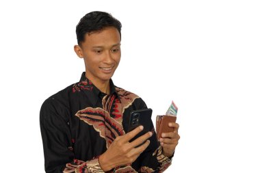 İçinde para olan bir cüzdan ve mutlu bir ifadeyle cep telefonu tutan Asyalı bir adam.