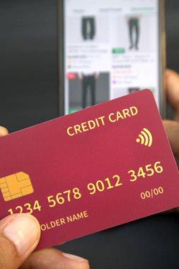 Adamın elinde cep telefonundaki internet dükkanının bulanık arkaplanlı kredi kartı var.