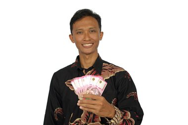 Asyalı bir adam mutlu bir ifadeyle bir sürü rupiah parası tutar.