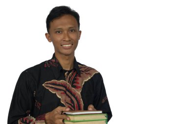 Asyalı bir adam neşeli bir ifadeyle kitap taşıyor.